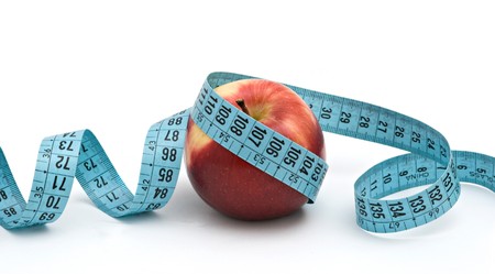 An apple with measuring tape isolated on white background