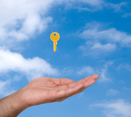 Close up of hand  and golden key on sky background の写真素材