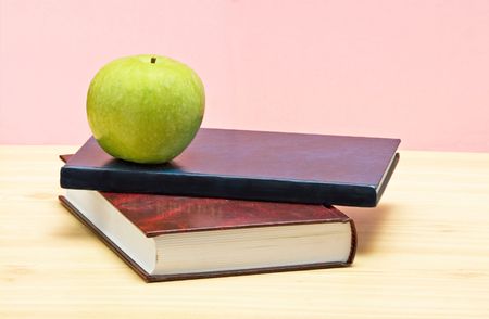 Green apple on books on deskの写真素材