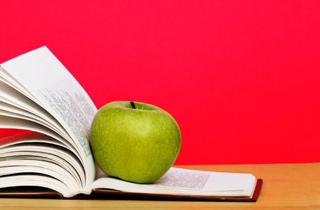 Green apple and open book on deskの写真素材