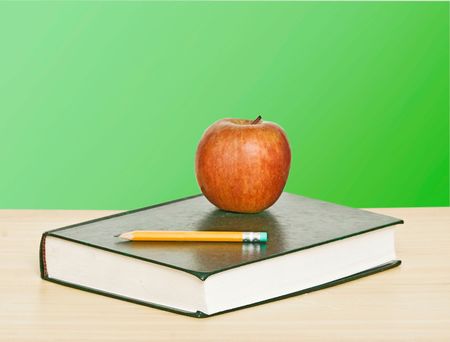 Red apple and pencil on top of bookの写真素材