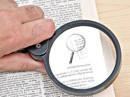 Attentive reader reading dictionary with magnifier glassの写真素材