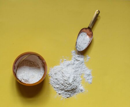 Floured flour on a yellow background, a copper pot of flour and a cooking scoop, horizontalの写真素材
