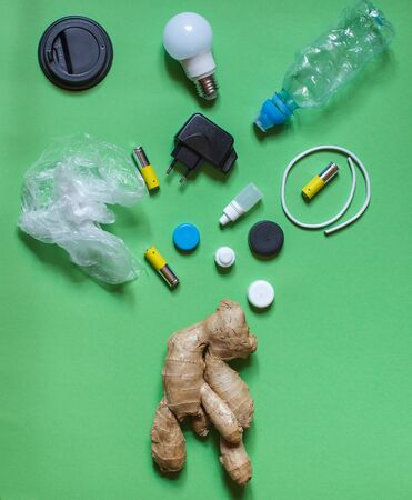ugly ginger root with various types of household waste, incandescent lamps, batteries, plastic on a green background, on topの写真素材