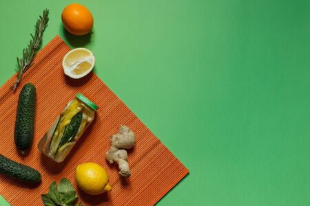 Sassi water and cooking ingredients, fresh cucumber, root, ginger, lemon, mint on an orange bamboo...
