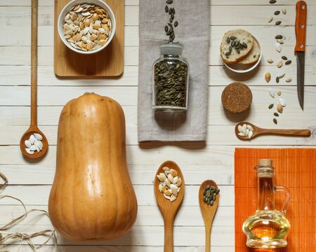 flatlay with pumpkin lagenaria, wooden spoons of different sizes , peeled and unpeeled pumpkin seeds, linen napkin and a glass jar with oilの写真素材