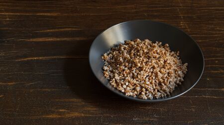 Buckwheat porridge in a gray plate on a dark wooden table with spaceの写真素材