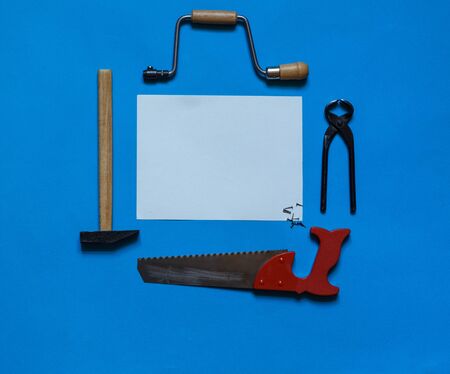 Carpenter mini tools on blue with a white blank signature card in the centerの写真素材