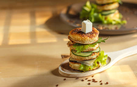 sandwich of mini pancakes, greens and cheese on a wooden spoon, horizontally with spaceの写真素材