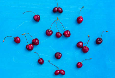 layout of unusual cherries with ugly growths, fused, on a blue background, top view