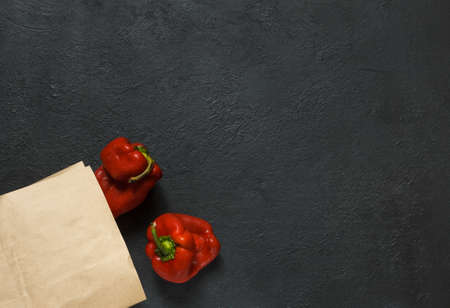 Two ugly red peppers with a paper bag on a black background with space