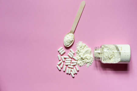 Dietary Supplement for skin and joints in powder and pills on a pink background. Top view, horizontally with spaceの写真素材