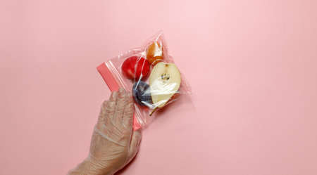a hand in a protective glove holds a Breakfast bag with healthy fruit for a snack