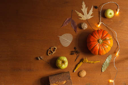 Autumn holiday flatlay with orange small pumpkin, glowing garland and dry leaves. Top, copy of spaceの写真素材