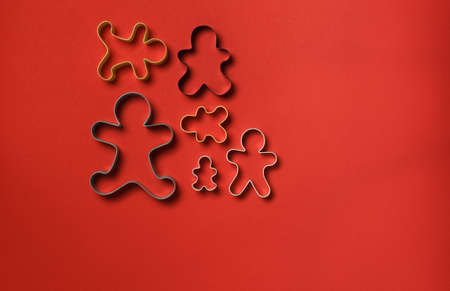 Gingerbread man family baking molds for Christmas. On a red paper background, layout with space. Overheadの写真素材
