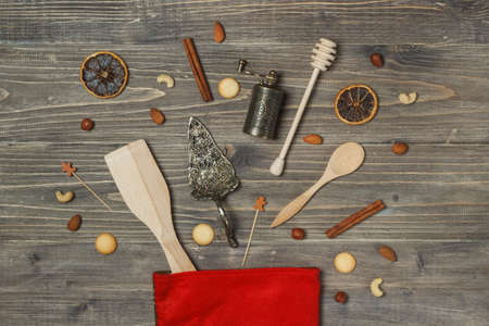 Festive new years background. Kitchen supplies, spices, nuts and cookies in a Red sock for gifts. Overhead layout on a dark wooden background with spaceの写真素材