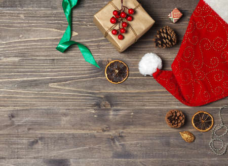 Red Santa Claus Hat, gift box, holiday decor and ribbons on a dark wooden background, with space. Top viewの写真素材