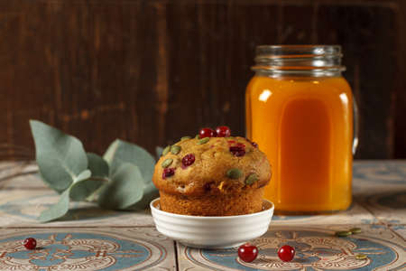 Homemade muffin and a glass of sea buckthorn tea on a dark wooden background, close-up