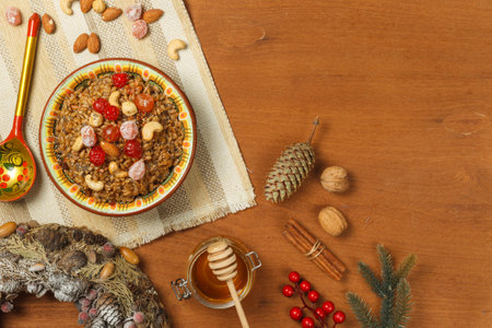 Kutia, a porridge made from wheat with nuts, poppy seeds, berries and dried fruits. On a wooden background with fir branches and cones. Top view with spaceの写真素材