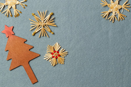 New Year's layout with handmade Christmas toys made of natural materials. Wooden Christmas tree and straw snowflakes on a gray backgroundの写真素材
