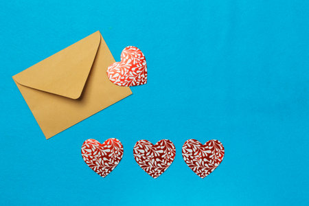 a letter, an invitation in an envelope, and shiny paper hearts with patterns. Layout with space for text, horizontal, on a blue background. Please your loved ones by staying in isolation.の写真素材
