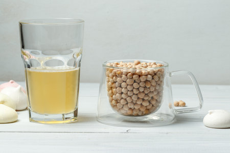 Chickpea grains in a glass Cup and aquafaba, the liquid obtained after decocting chickpeas or beans, is used in cooking instead of eggsの写真素材