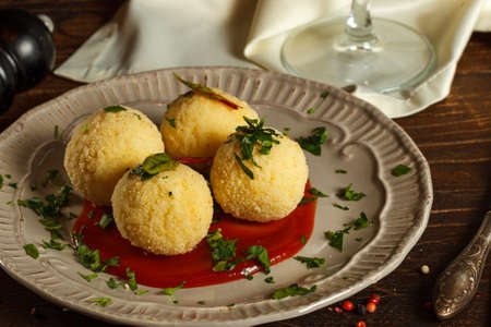 Arancini, rice balls with filling on a gray plate with sauce. Close up. Popular street food,...