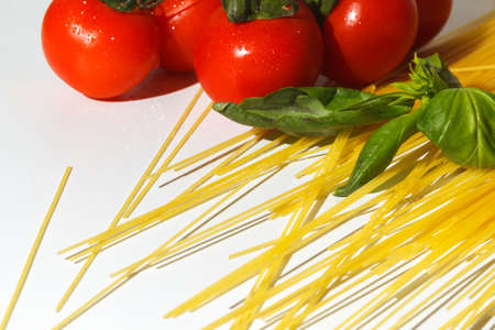 The concept of preparing for the preparation of delicious pasta. Scattered spaghetti, tomatoes and basil. Ingredients for making pasta bologneseの写真素材