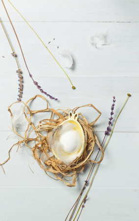Easter, spring content. Egg in a bowl with rabbit ears, on a light wooden background, vertically, top viewの写真素材