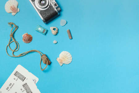 Vintage camera, seashells and pebbles, and a beach charm on a rope. The concept of goals, plans for a vacation. Layout on a blue background with spaceの写真素材