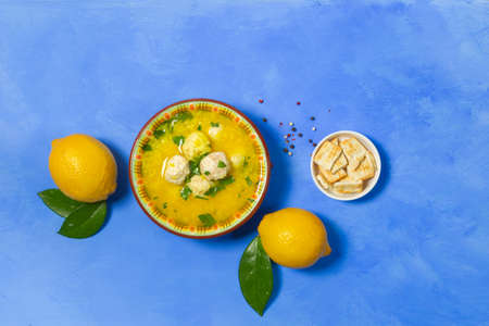 Avgolemono, Greek traditional soup, antioxidant. Chicken soup with egg yolks and lemon juice. On a blue background with lemons. Layoutの写真素材