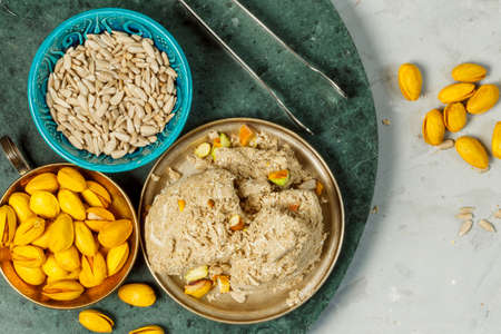Sunflower seed halva with pistachios in small vintage bowls. Halva is a natural healthy treat made from whipped caramel and ground nuts and seeds. Close-up, top viewの写真素材