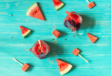 Refreshing watermelon smoothie with red basil. Overhead, with watermelon slices on a blue wooden backgroundの写真素材