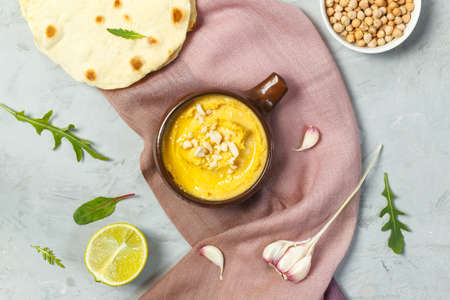 Hummus, a traditional chickpea paste with garlic, lemon, tahini and spices. Vegetarian snack snack, used for sandwiches, rolls, pita bread. Top view on a gray backgroundの写真素材
