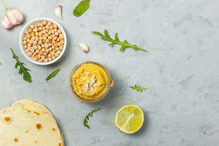 Hummus, a healthy vegetarian chickpea paste, is a source of vegetable protein. Served with tortillas. On a gray background, overhead, with spaceの写真素材