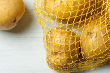 Fresh unpeeled potatoes in the grid. Natural background with vegetables. Close up, with copy spaceの写真素材