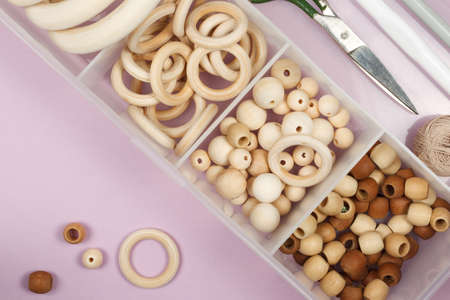 A set of wooden beads, rings for making crafts for children, jewelry, rattles, amigurumi. In a plastic organizer, close-up, top view, copy of the space, horizontalの写真素材