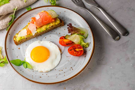 Light and hearty breakfast, brunch with fried eggs, toast on grain bread with smoked salmon and...
