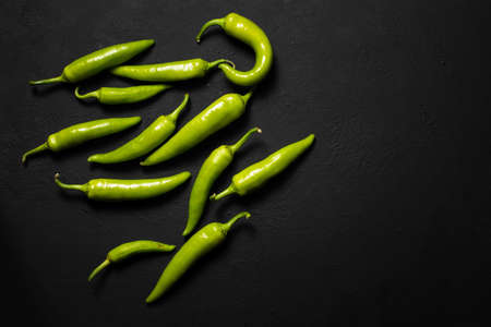 a pile of hot green chili peppers on a black surface. Top view, copy of the space, horizontalの写真素材