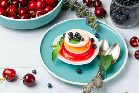 A portion of layered berry jelly on a blue plate. On a gray wooden background, horizontal