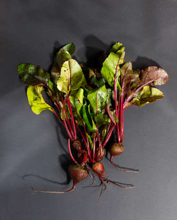 Fresh beetroot with tops on a black background. A vertical frame with space. Top view. raw...