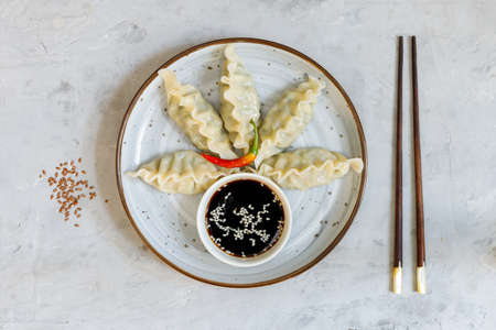 Japanese or Chinese boiled gyoza dumplings served with soy sauce. Top view on a gray stone background, with chopsticks. With space for text. Horizontal frameの写真素材