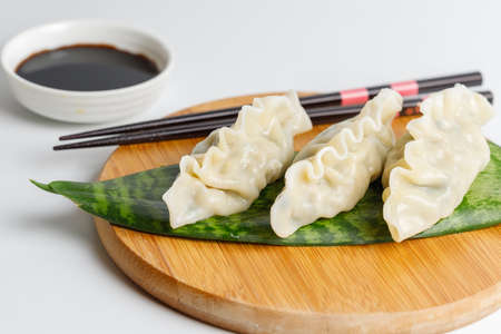 Japanese or Chinese national dish, gyoza dumplings with meat, seafood or vegetables. A portion of three dumplings on a round wooden stand. Close-upの写真素材