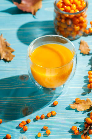 A glass with hot or refreshing sea buckthorn juice. A natural vitamin cocktail. Close-up on a blue...