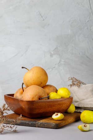 Sweet Chinese Nashi pears and quince in a wooden bowl. Still life with fruit. Vertical on a light gray backgroundの写真素材