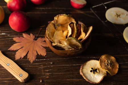 Dried apples or apple chips. A healthy snack. Close-up on a dark wooden table. With apples, autumn...