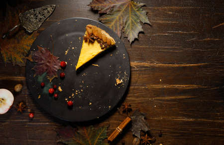 Autumn concert ,festive table.The last piece of pumpkin pie on a black plate. Flatlay on a dark wooden background with bright autumn leaves.の写真素材