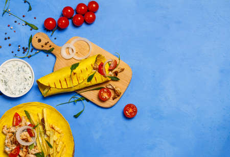 Local cuisine, Greek shawarma gyros with chicken meat, French fries, vegetables and zadziki sauce. On a blue background, a flatlay, a copy of the spaceの写真素材