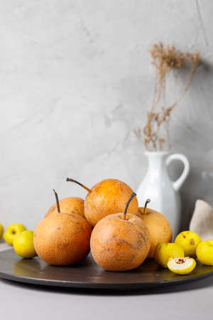 Still life with nashi pears and quince on a black plate. Vertical on a gray backgroundの写真素材
