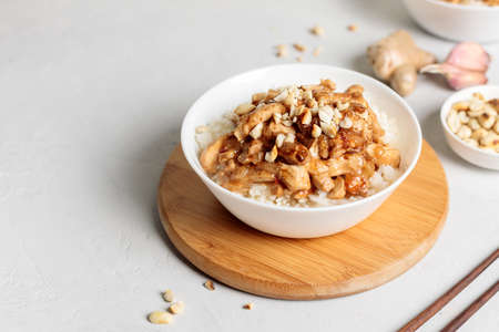 Chinese cuisine. A popular dish is Kung pao, pieces of chicken fillet in a sauce with peanuts and hot chili pepper. Close-up on a light background, horizontal with spaceの写真素材